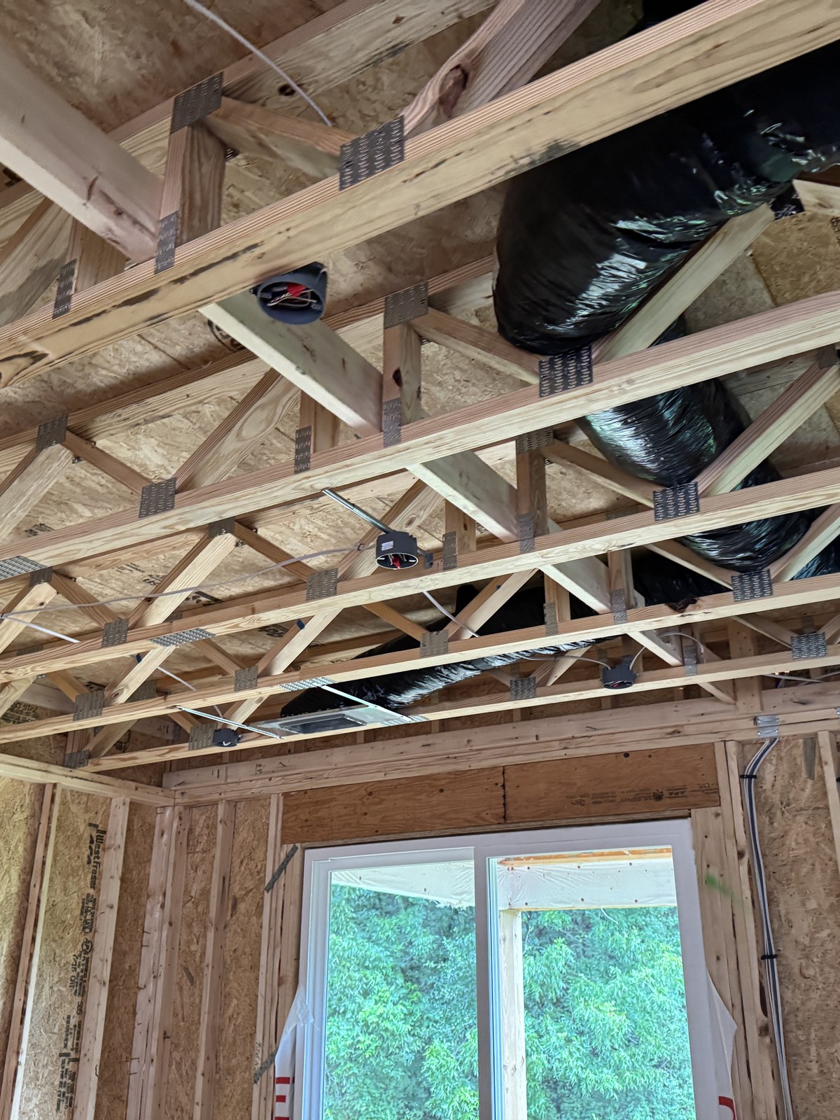 Floor trusses, ductwork, and wiring overhead inside a Hornet home mid-build.